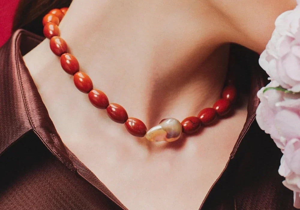 Model wearing the Fenella golden baroque pearl necklace with a burgundy satin blouse