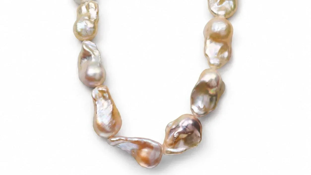 Elysian golden baroque pearl necklace arranged as a full strand on a light gray background