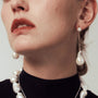 Woman wearing the Luisy mismatched asymmetric baroque pearl gold drop earrings