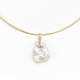 Close-up of iridescent baroque pearl pendant on gold snake chain