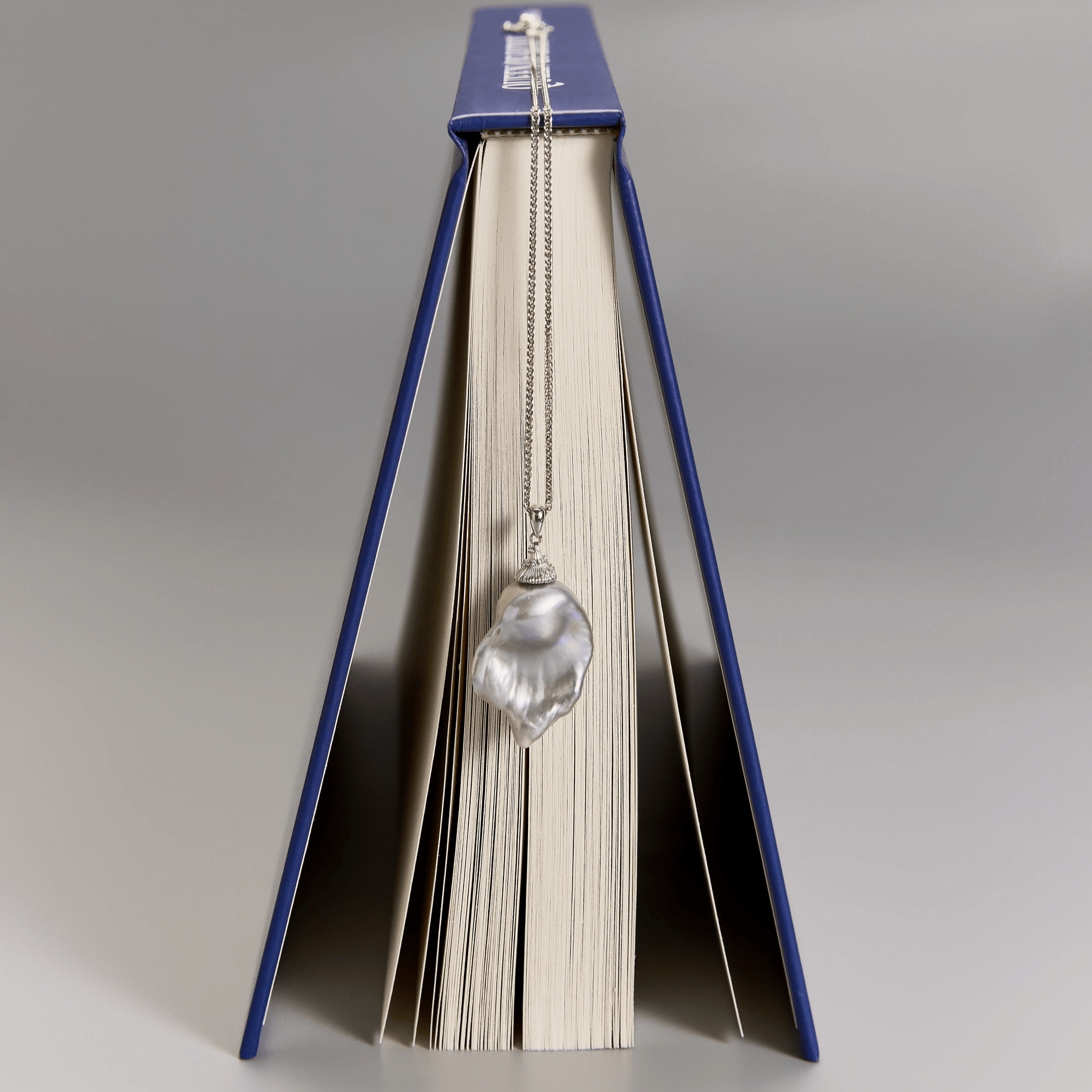 Close-up of gray baroque pearl pendant with book styling