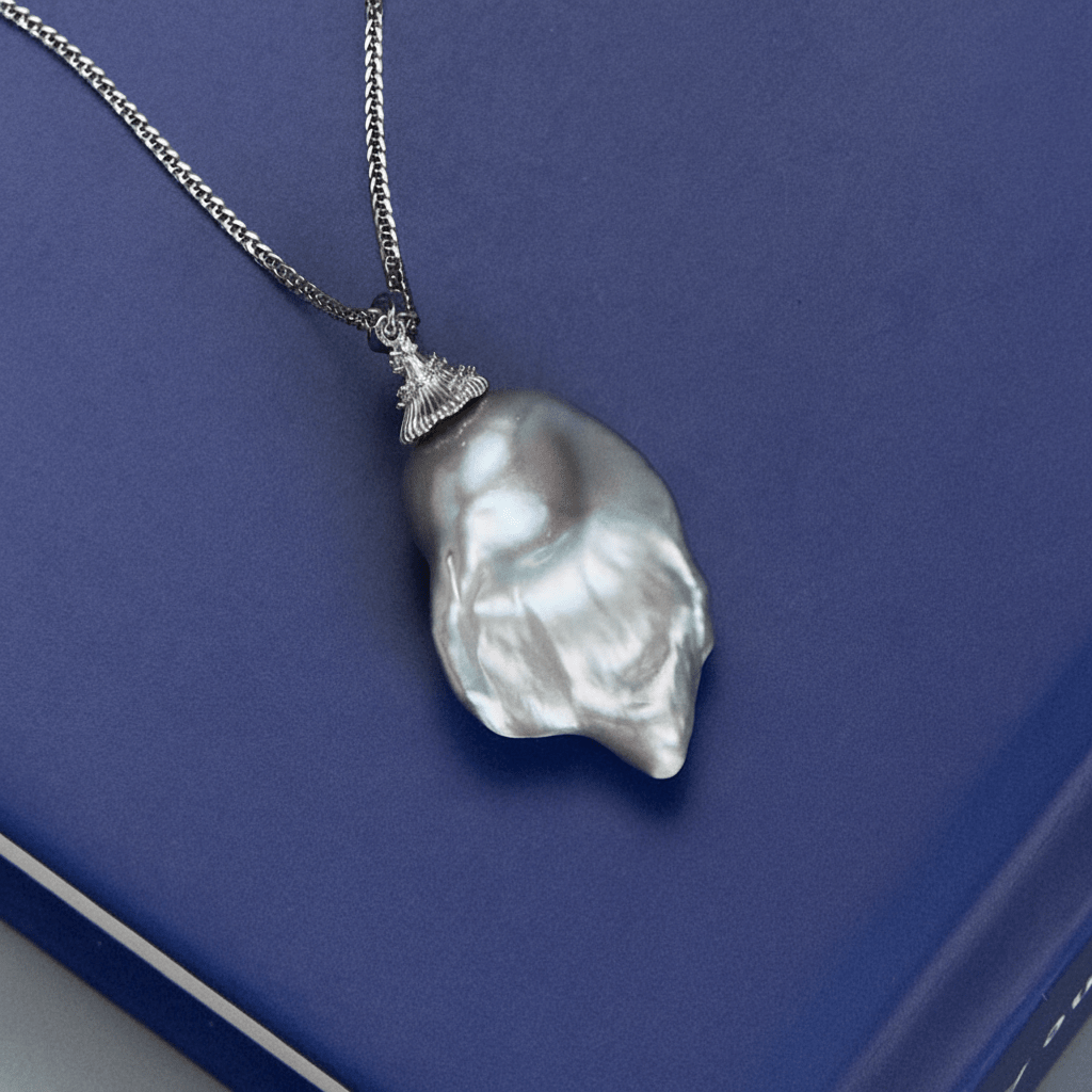Isolated close-up of gray baroque pearl pendant and chain