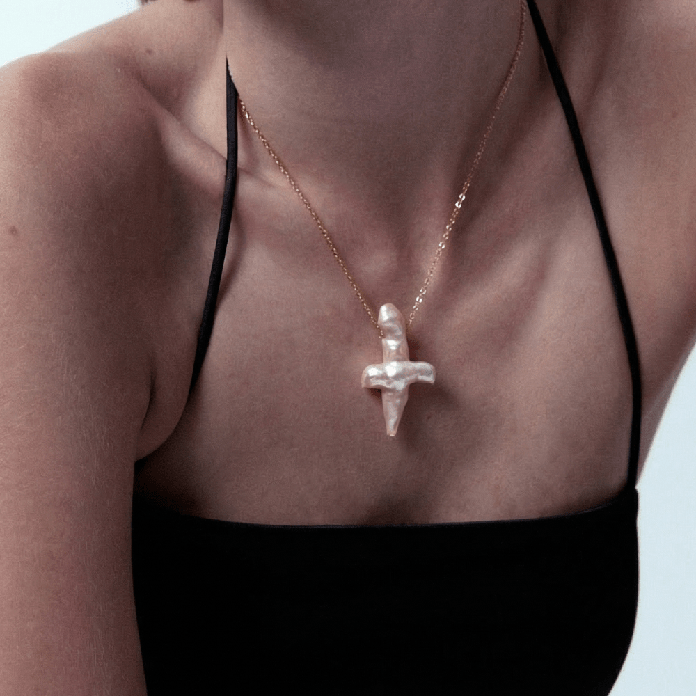 Model wearing a unique cross shaped pearl pendant on a premium 18K gold-plated chain.