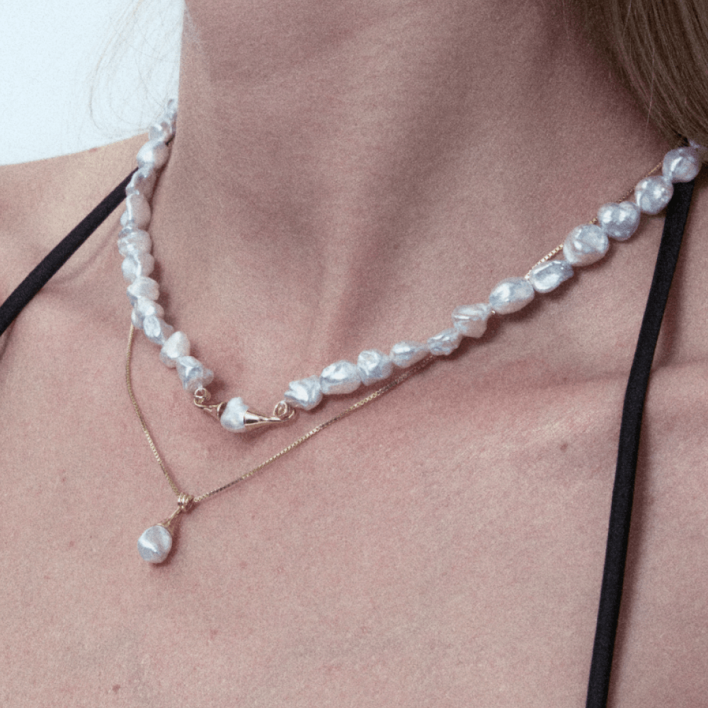 Model styling pearl pendant for everyday quiet luxury outfit