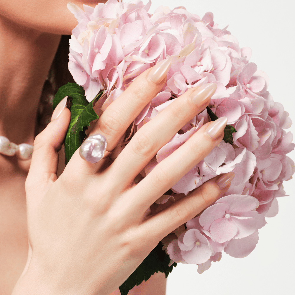 Close-up of baroque pearl ring on model's hand with pink hydrangea bouquet