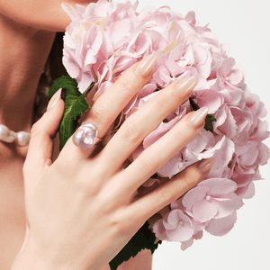 Close-up of baroque pearl ring on model's hand with pink hydrangea bouquet