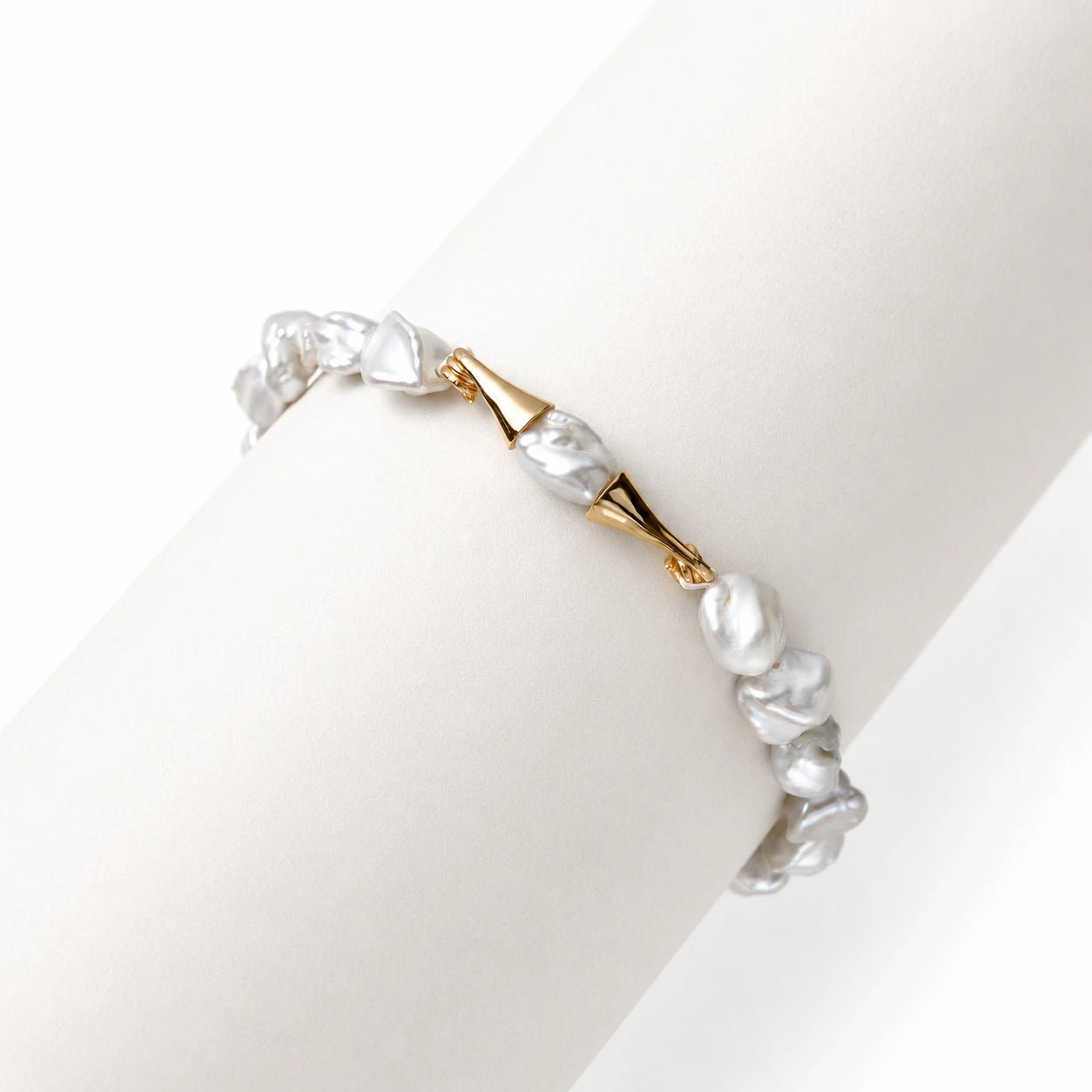 Close-up of iridescent blue keshi pearls and 18k gold curved accents on bracelet
