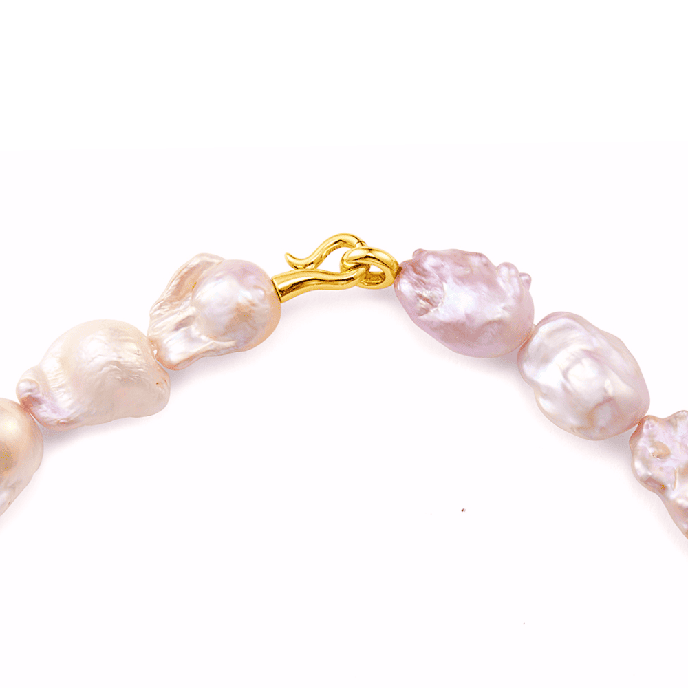 Close up of irregular pink freshwater baroque pearls and gold S clasp detail