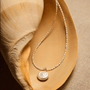 Coin pearl necklace styled on seashell background
