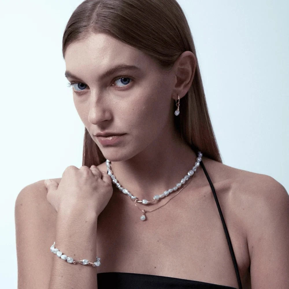Soft muted studio portrait of model layered with full mini keshi pearl set, lightweight petite keshi jewellery with slim gold hardware, slim black camisole styling