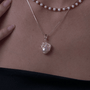 Close-up of pink luster baroque pearl pendant on gold chain on model