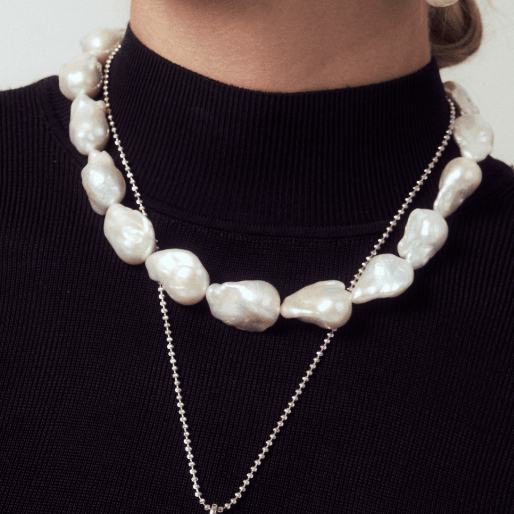 Wearing a statement piece large natural pearl necklace, perfect for date night looks for women.