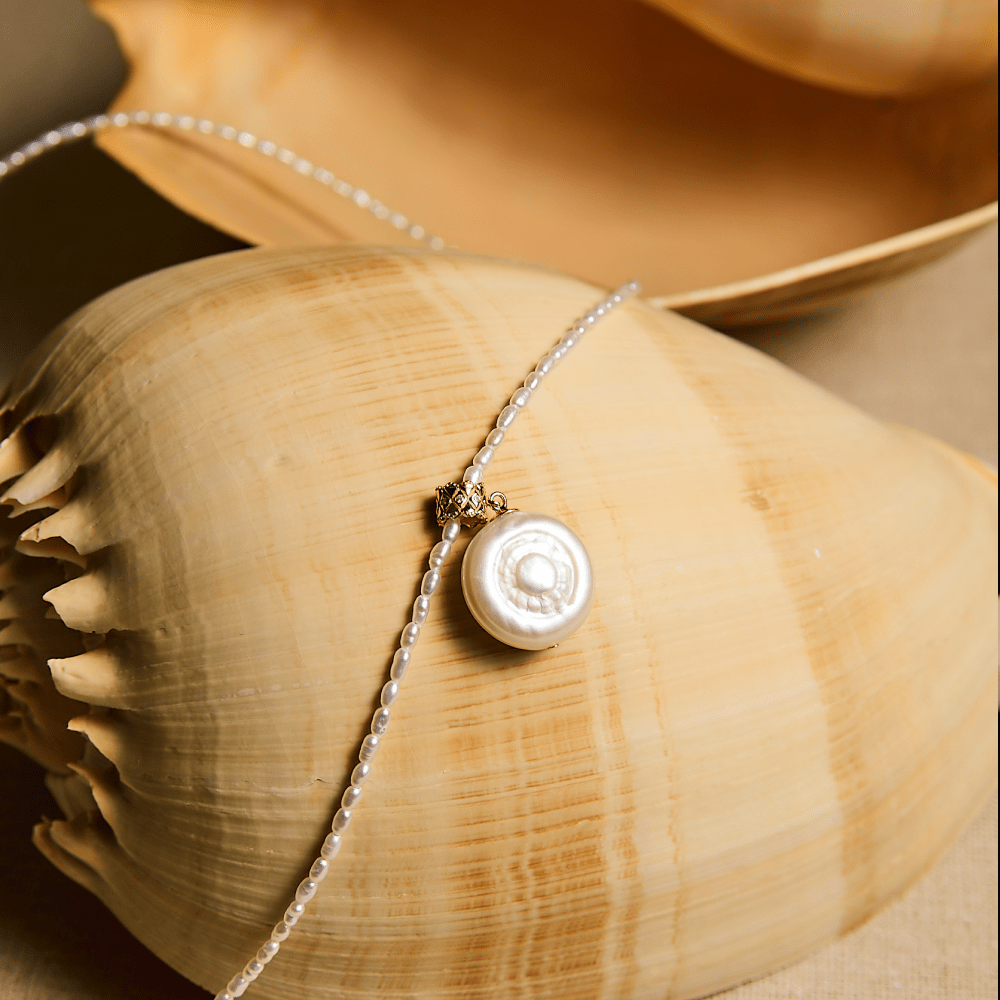 Close-up of coin baroque pearl pendant on seashell styling