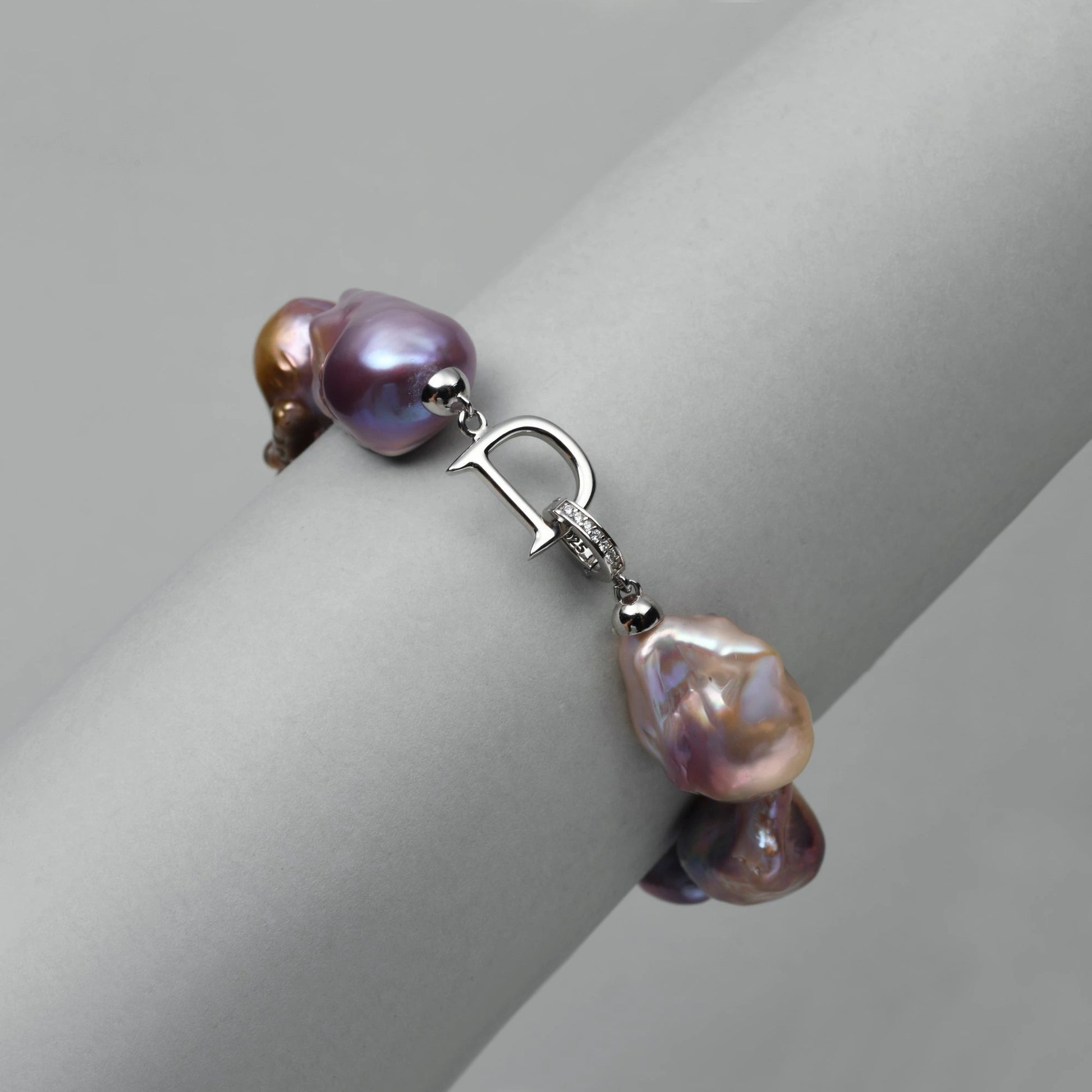 Plain white studio shot showcasing polished anti-tarnish 925 sterling silver safety box clasp attached to purple tidal baroque pearl strand