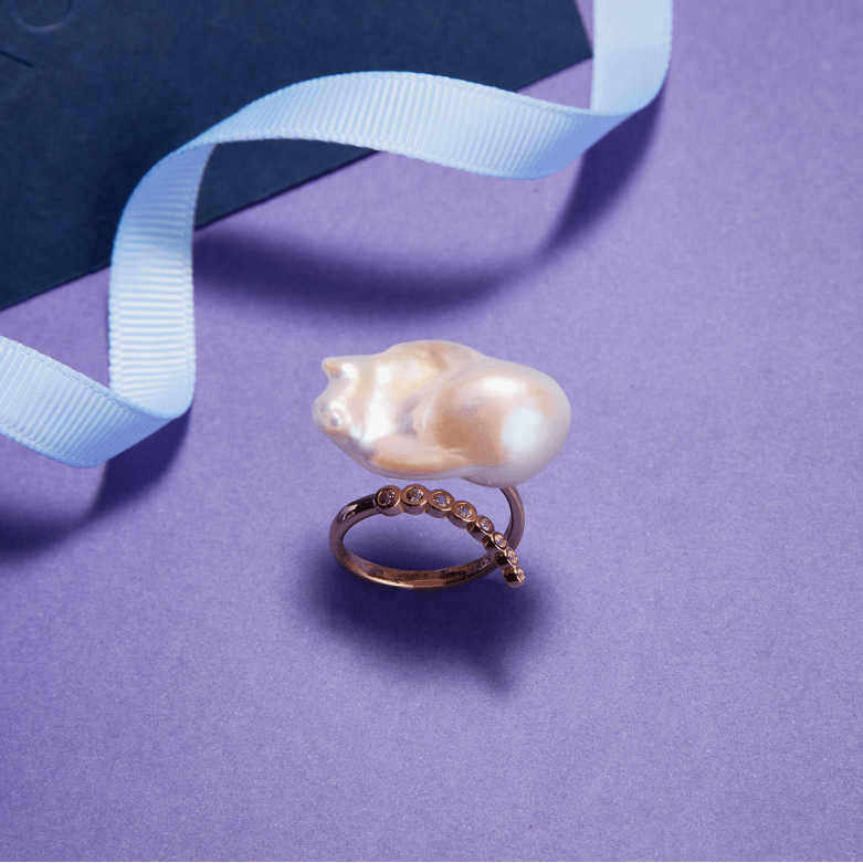 Baroque pearl ring styled on purple background with gift ribbon