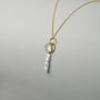 Side view of 18k gold orbit baroque pearl pendant on neutral background