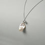 Side view of mini drop pearl pendant on neutral background
