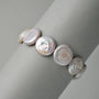 Neutral grey close-up highlighting soft shifting iridescent luster and subtle natural edge irregularities of flat coin-shaped white button baroque freshwater pearls