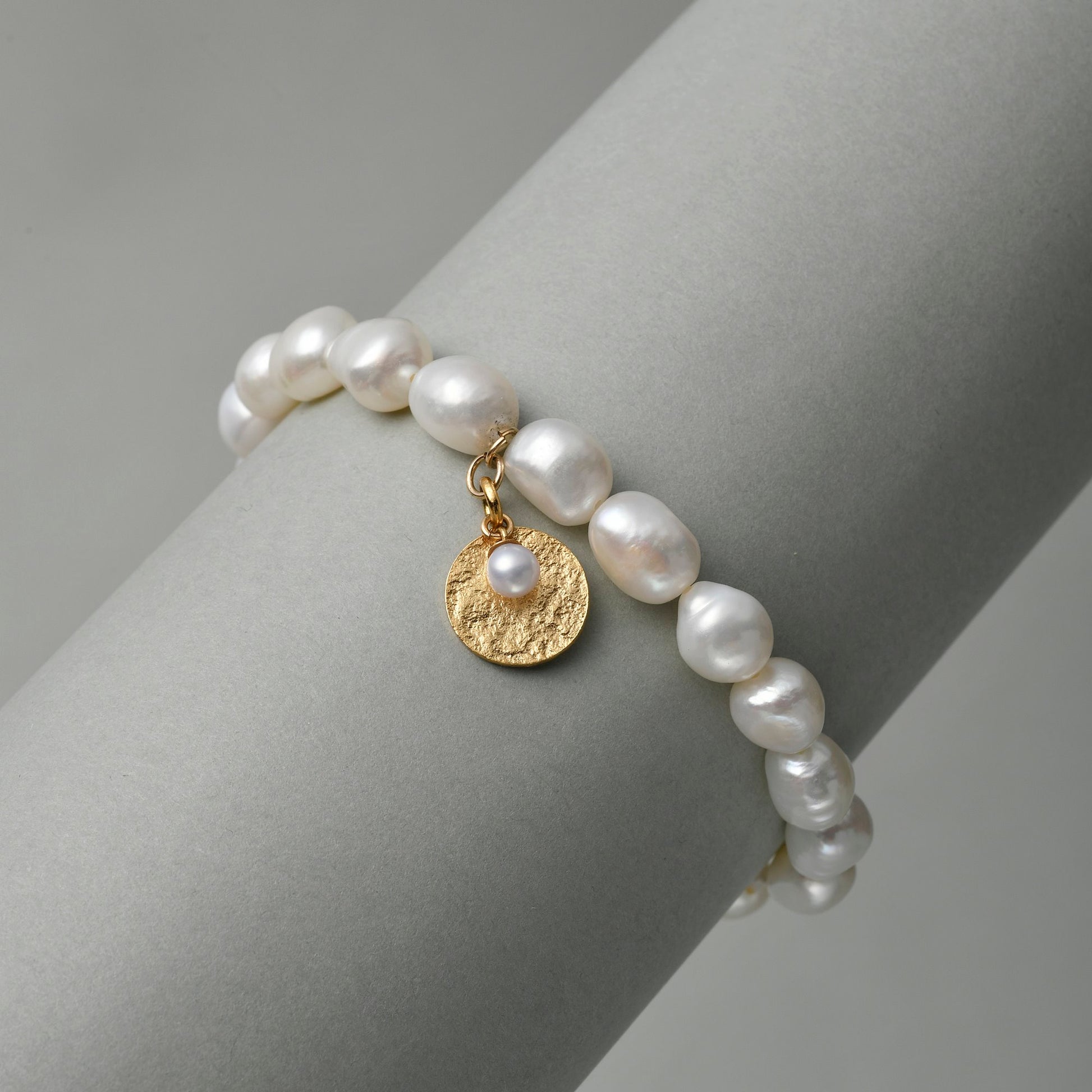 Side view of the button pearl bracelet with gold charm