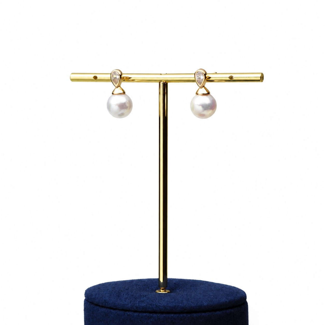 Solace drop pearl earrings on gold display stand (front view)
