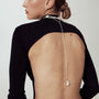 Full back soft shot of woman in thin backless white top showcasing asymmetrical Y-lariat baroque pearl drop necklace, delicate cascading pearl chain silhouette