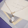 Top-down minimal white flat lay of full adjustable Y-lariat pearl necklace, complete oval rice pearl strand and large baroque drop pendant fully visible