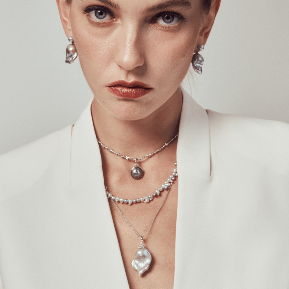 Model styling the pearl necklace with formal layered jewelry