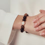 Neutral close-up shot of unisex model’s hands stacked with wood pearl stretch bracelet against crisp white blazer, quiet office minimalist daily styling