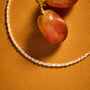 Warm summer styled shot of keshi pearl wrap anklet placed on terracotta surface, soft casual vacation aesthetic