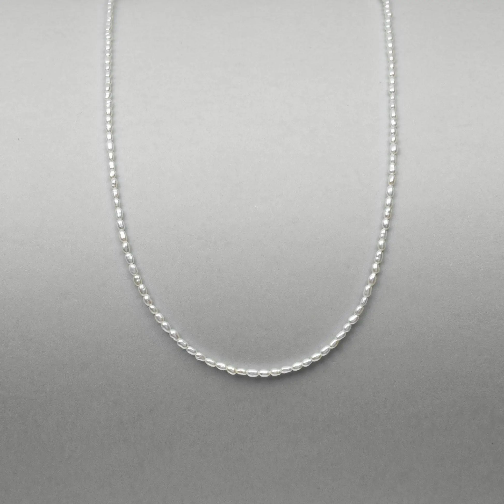 Close-up product shot of spring ring clasp and silver gold-plated hardware connected to fine keshi pearl strand.