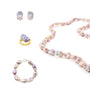 Flat lay studio shot of complete four-piece purple baroque pearl jewelry set, matching necklace, bracelet, ring and stud earrings arranged on clean solid white background