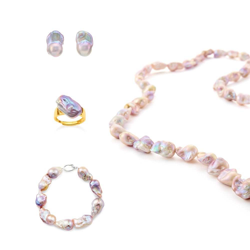 Flat lay studio shot of complete four-piece purple baroque pearl jewelry set, matching necklace, bracelet, ring and stud earrings arranged on clean solid white background